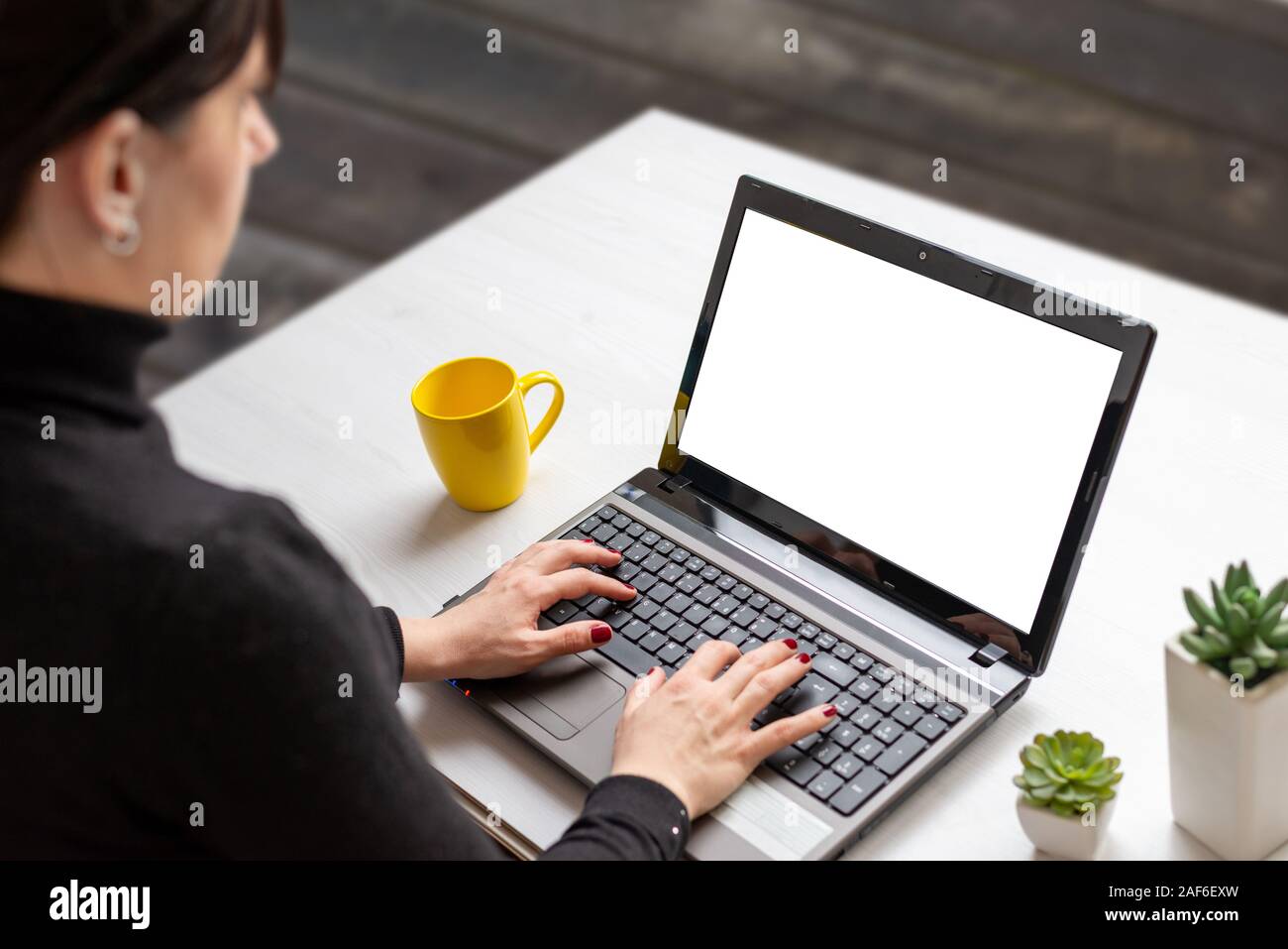 Frau Arbeit auf Laptop mit isolierten Bildschirm für Mockup auf weißen flachen Schreibtisch mit Tasse Kaffee und Anlagen Stockfoto
