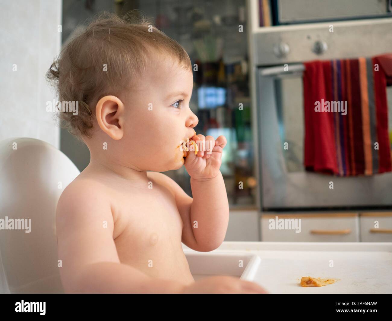 1 Jahr alte Hündin Baby sitzt auf einem hohen Stuhl warten auf Ihre Mahlzeit Stockfoto