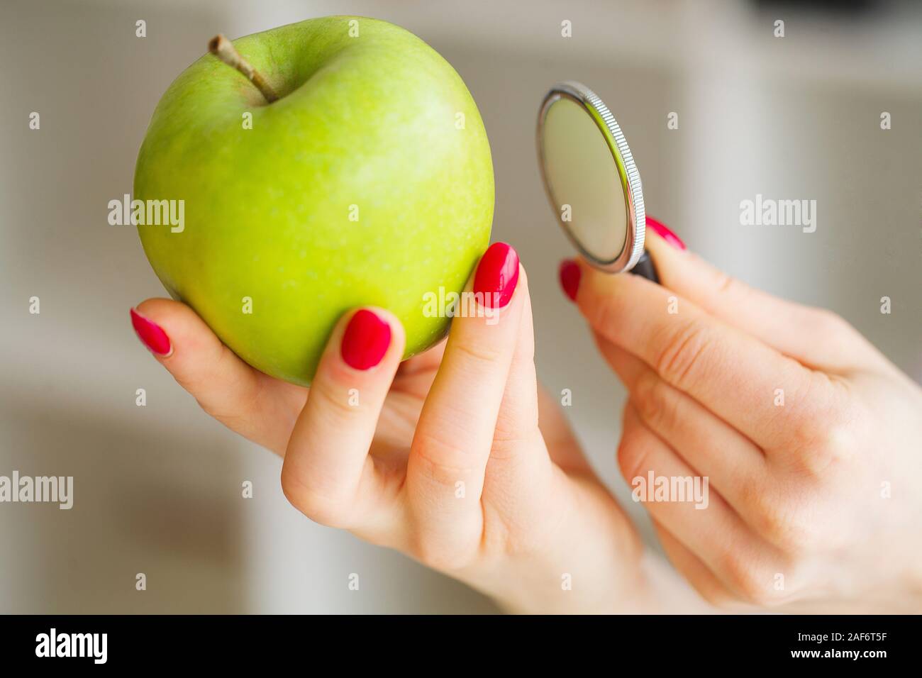 Gesundheit. Das gesunde Essen. Die Ernährungsberaterin hält in den Händen von frischen, grünen Apfel. Frisches Obst und Gemüse auf den Tisch. Gerne Arzt. Hohe Stockfoto
