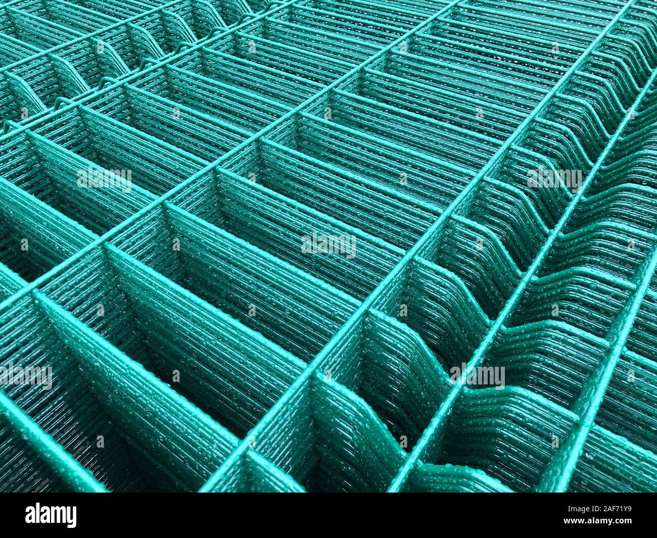 Regen fällt auf grün gefärbten Metallgitter. Stockfoto
