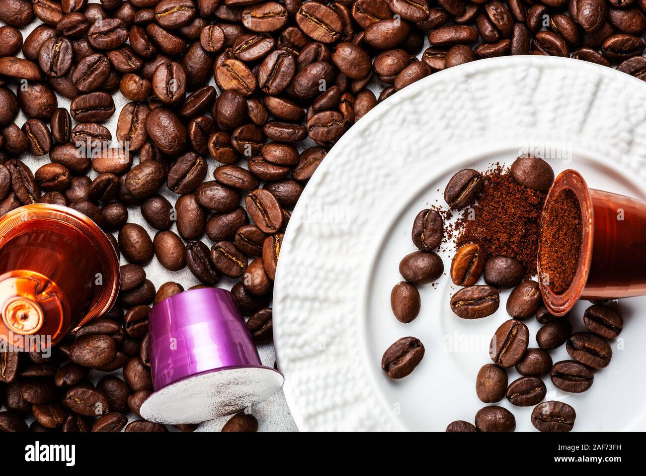 Öffnen Espresso Kaffee Kapseln oder Hülsen und Kaffeebohnen auf grauem Hintergrund, Ansicht von oben. Vorbereitung für morgendliche Tasse Kaffee Konzept Stockfoto