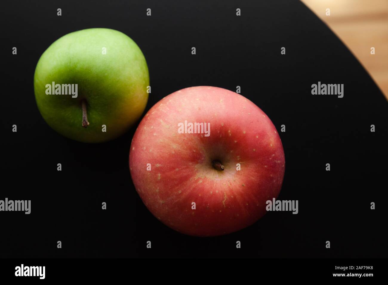 Zwei Äpfel grüne und rote lag auf einem schwarzen Schreibtisch, Ansicht von oben. In der Nähe von low-key Foto mit weichen selektiven Fokus Stockfoto
