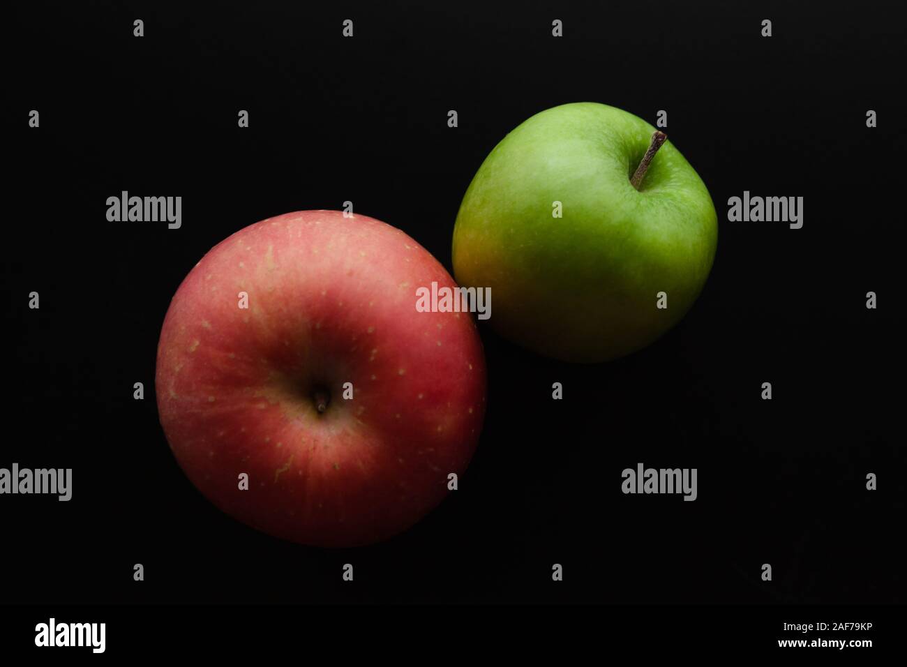 Zwei Äpfel grüne und rote lag auf einem schwarzen Schreibtisch, Ansicht von oben. In der Nähe von low-key Foto mit weichen selektiven Fokus Stockfoto