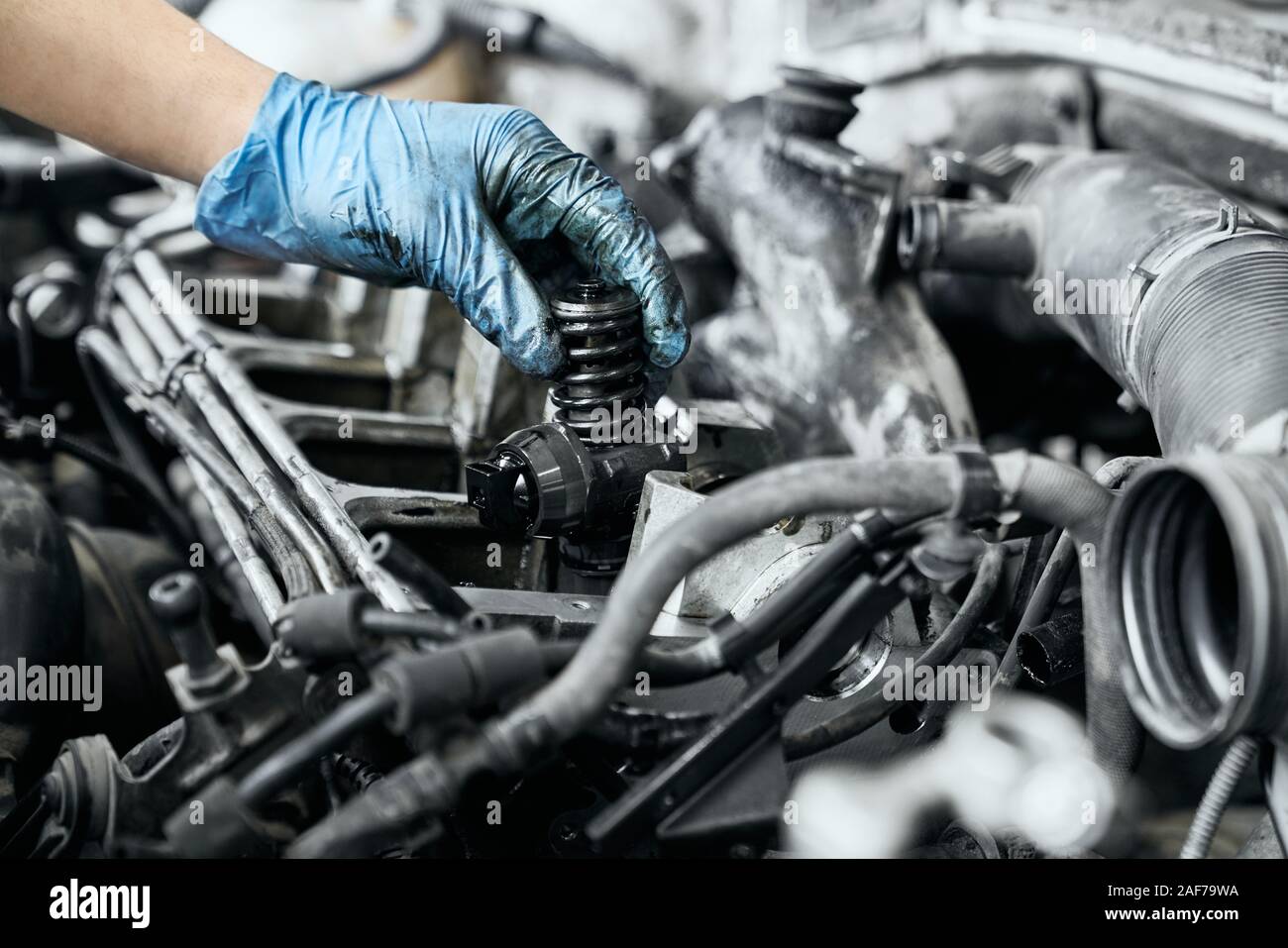 Professionelle Mechaniker in schmutzigen Schutzhandschuhe testen Gerade installierte Düse in Diesel Auto Motor Motor zu gewährleisten. Konzept der Instandsetzung Stockfoto