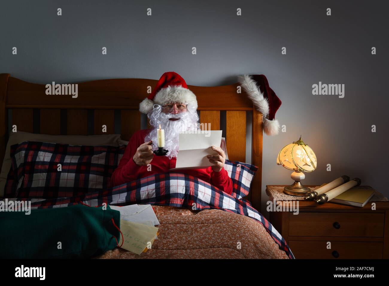 Santa Claus lesen Buchstaben bei Kerzenschein im Bett an seinem Nordpol Heimat. Stockfoto