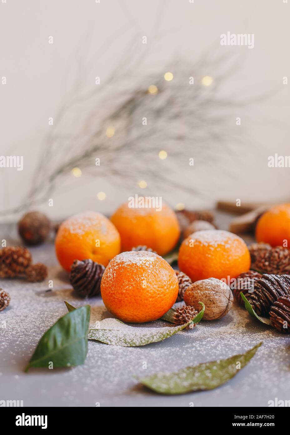 Orange Mandarinen auf grauem Hintergrund im Neuen Jahr Einrichtung mit braunen Tannenzapfen und grünen Blättern. Köstlich süßen Clementine. Weihnachtsdekoration mit Stockfoto