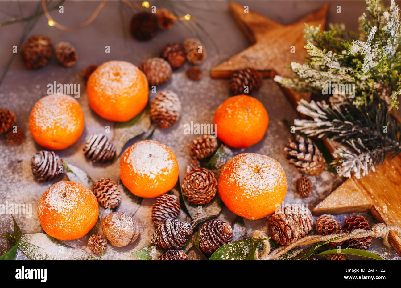 Orange Mandarinen auf grauem Hintergrund im Neuen Jahr Einrichtung mit braunen Tannenzapfen und grünen Blättern. Köstlich süßen Clementine. Weihnachtsdekoration mit Stockfoto