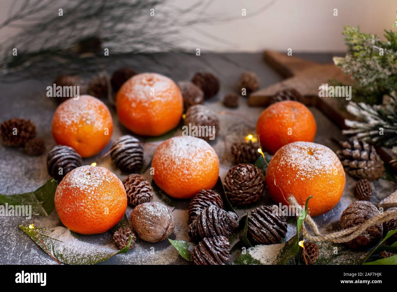 Orange Mandarinen auf grauem Hintergrund im Neuen Jahr Einrichtung mit braunen Tannenzapfen und grünen Blättern. Köstlich süßen Clementine. Weihnachtsdekoration mit Stockfoto