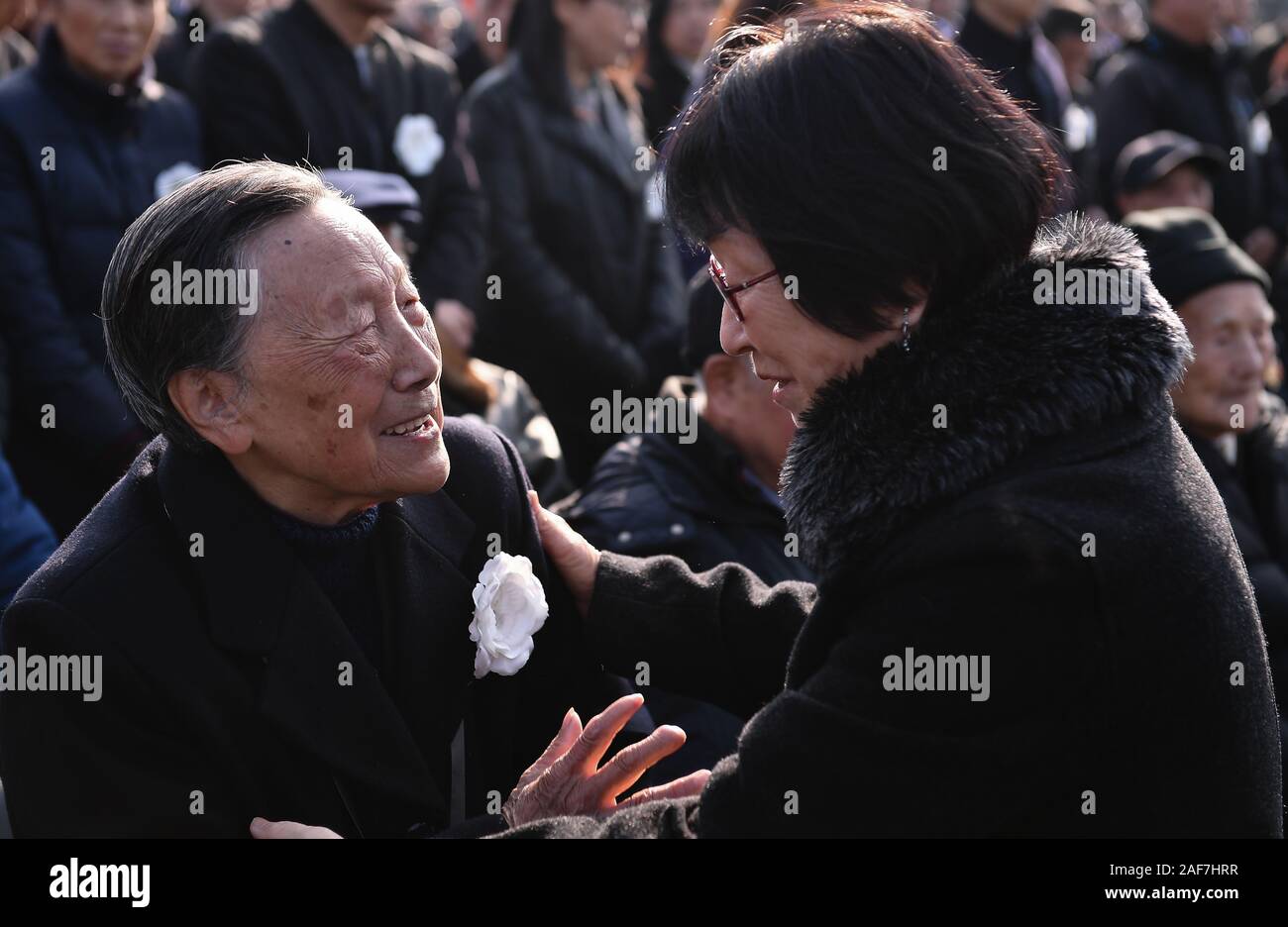 (191213) - NANJING, Dez. 13, 2019 (Xinhua) - Überlebende des Massakers von Nanjing Xia Shuqin (L) spricht mit einem japanischen Freund während der nationalen Gedenkfeier für die Opfer der Nanjing Massaker an der Memorial Hall der Opfer des Massakers von Nanjing durch die Japanischen Invasoren in Nanjing, der Hauptstadt der ostchinesischen Provinz Jiangsu, Dez. 13, 2019. Vor der Masse in Schwarz, Chinas nationale Flagge flog auf Halbmast als die Nation einer Trauerfeier Freitag statt der 300.000 Opfer des Massakers von Nanjing zu trauern. Fixieren eine weiße Blume, mehr als 8.000 Menschen aus allen Gesellschaftsschichten nahmen an der Stockfoto