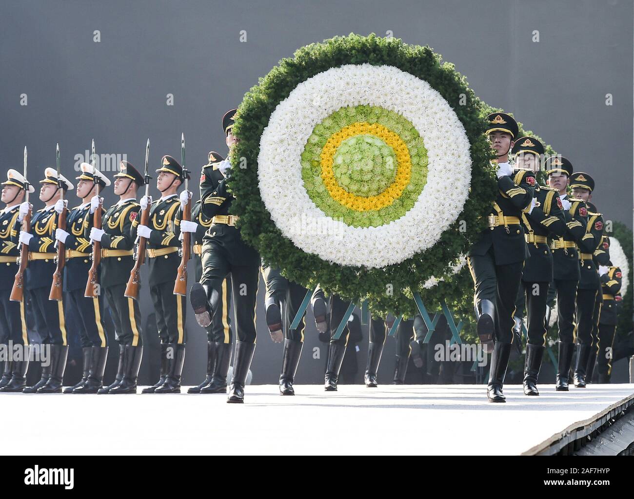 (191213) - NANJING, Dez. 13, 2019 (Xinhua) -- Soldaten tragen Kränze während der nationalen Gedenkfeier für die Opfer der Nanjing Massaker an der Memorial Hall der Opfer des Massakers von Nanjing durch die Japanischen Invasoren in Nanjing, der Hauptstadt der ostchinesischen Provinz Jiangsu, Dez. 13, 2019. Vor der Masse in Schwarz, Chinas nationale Flagge flog auf Halbmast als die Nation einer Trauerfeier Freitag statt der 300.000 Opfer des Massakers von Nanjing zu trauern. Fixieren eine weiße Blume, mehr als 8.000 Menschen aus allen Gesellschaftsschichten der Sechsten nationalen Trauerfeier in Nanjing, Osten Kinn besucht Stockfoto