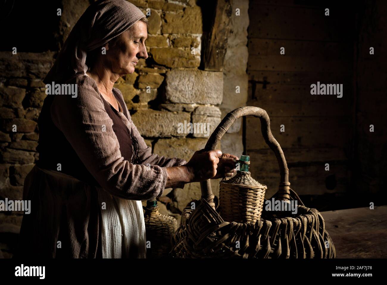 Die Frau in der mittelalterlichen Bauern ihr Kleid Nahrungsmittelkorb Kontrolle in den Kellern der eine Eigenschaft freigegeben Authentische mittelalterliche Schloss in Frankreich Stockfoto
