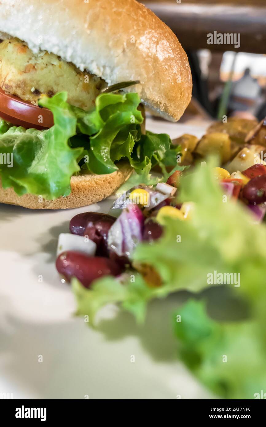 Gesunde vegane Burger mit Tomaten, gebackene Kartoffeln, Bohnen, Zwiebeln, Salat. Close-up. Stockfoto