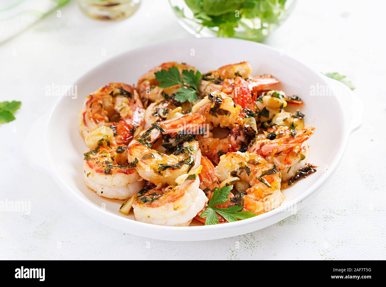 Gegrillte Garnelen. King Prawn Schwänze in Orange - Knoblauch Sauce mit Petersilie. Stockfoto