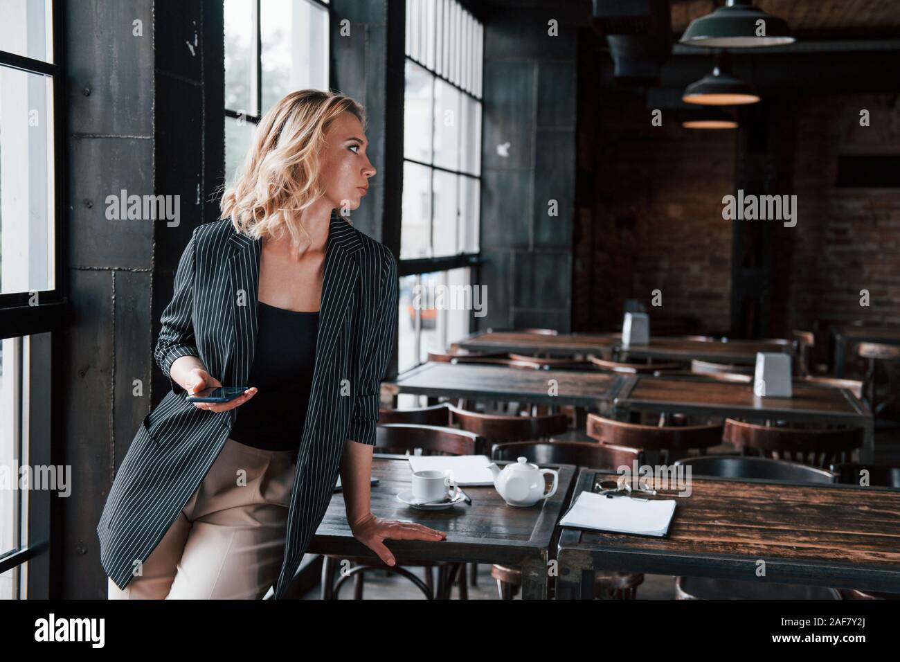 Drahtlose Technologien. Geschäftsfrau mit lockigem Haar drinnen im Café zu Tagfahrlicht Stockfoto