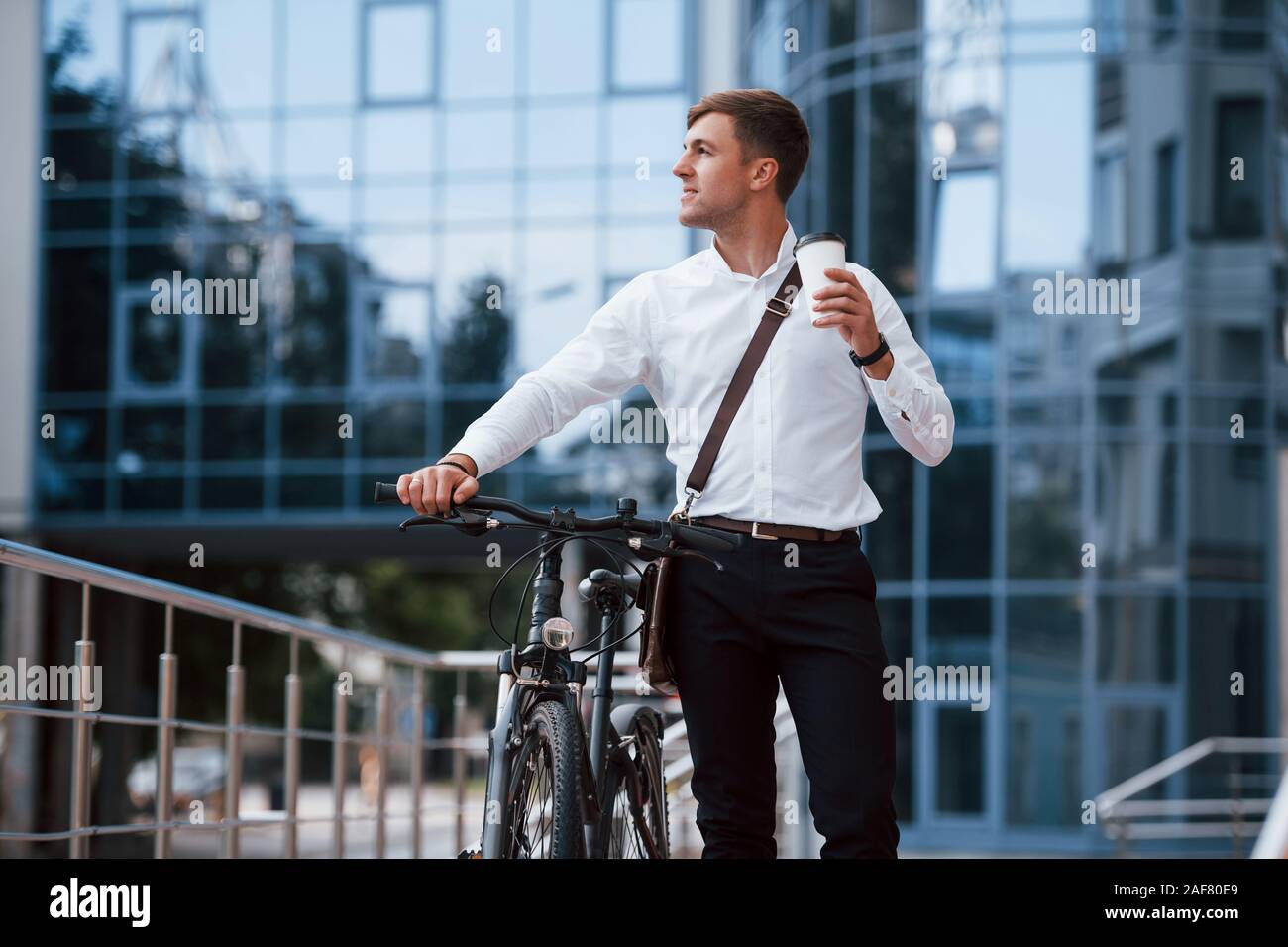 Die Schale mit frischen Getränken. Geschäftsmann in formelle Kleidung mit schwarzen Fahrrad ist in der Stadt Stockfoto