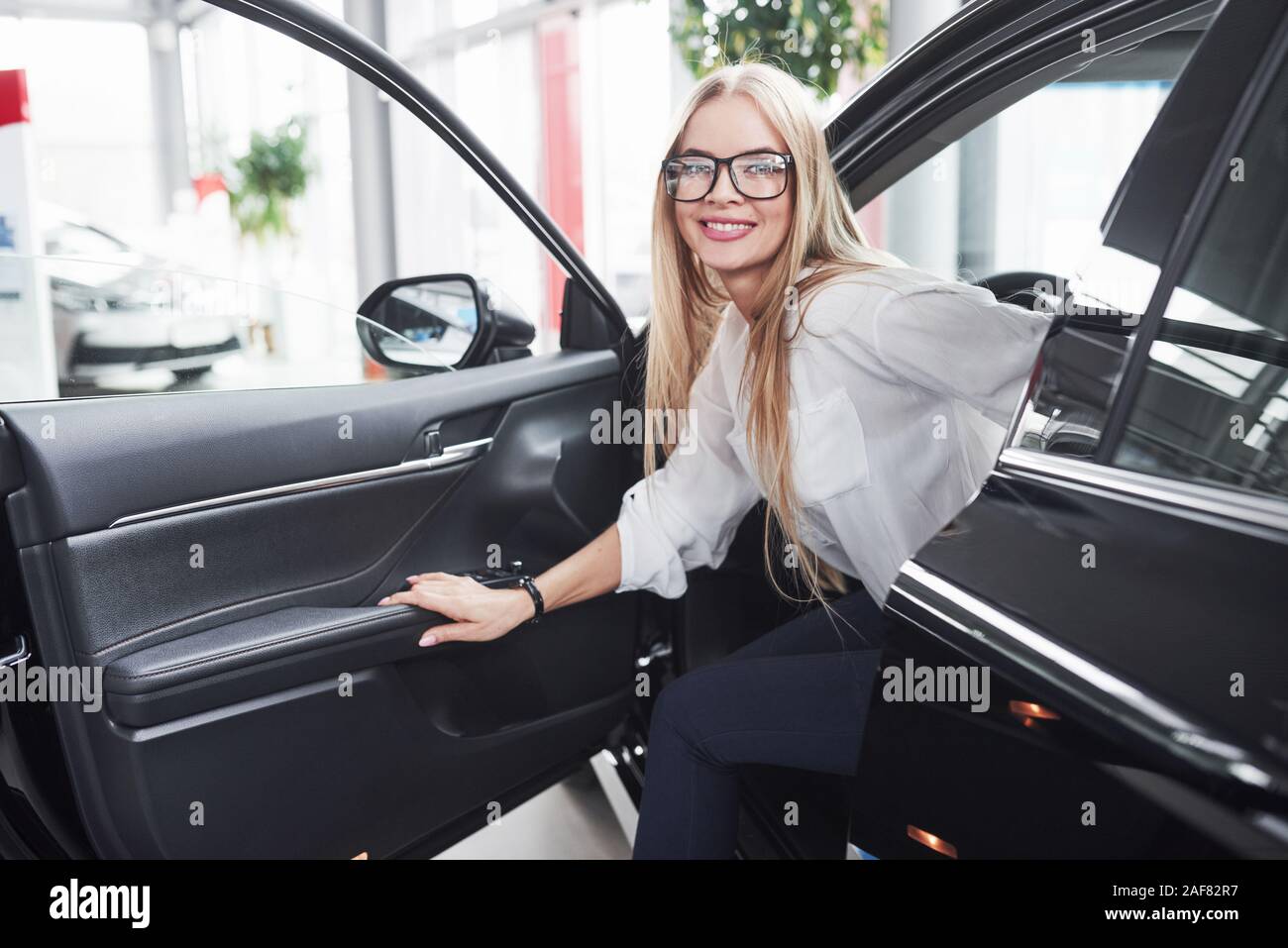 So, wie es sich anfühlt. Mädchen haben ihren neuen schwarzen Auto getestet. Sieht aus wie sie ist zufrieden Stockfoto