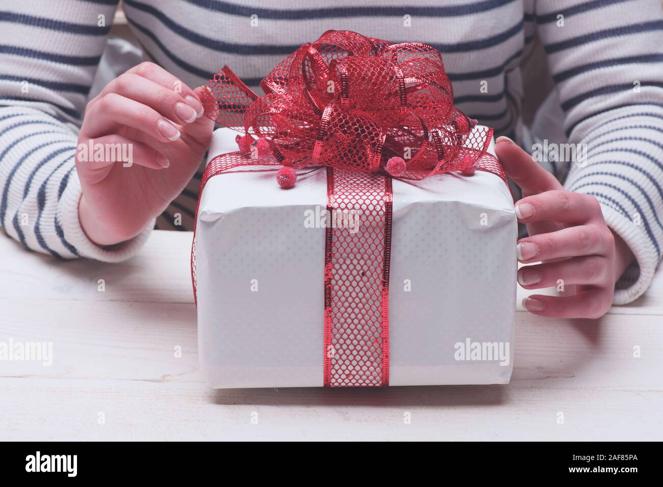 Weibliche Hande Halten In Weissem Papier Mit Roter Schleife Verpackt Geschenk Box Fur Heiligabend Mit Beeren Dekoration Geschenk Auf Hellen Hintergrund Urlaub Und Lassen Sie Sich Uberraschen Konzept Stockfotografie Alamy