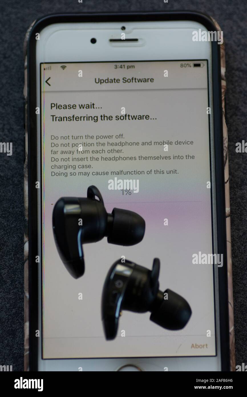 Drahtlose Ohrhörer werden über das Mobilteil aktualisiert Stockfoto