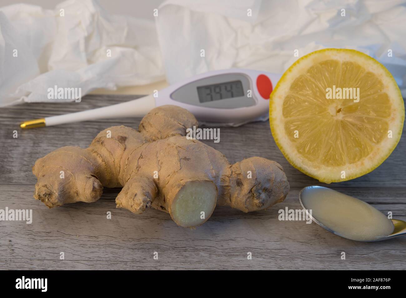 Fieberthermometer, eine Zitrone, Honig, Ingwer mit Gewebe im Hintergrund Stockfoto