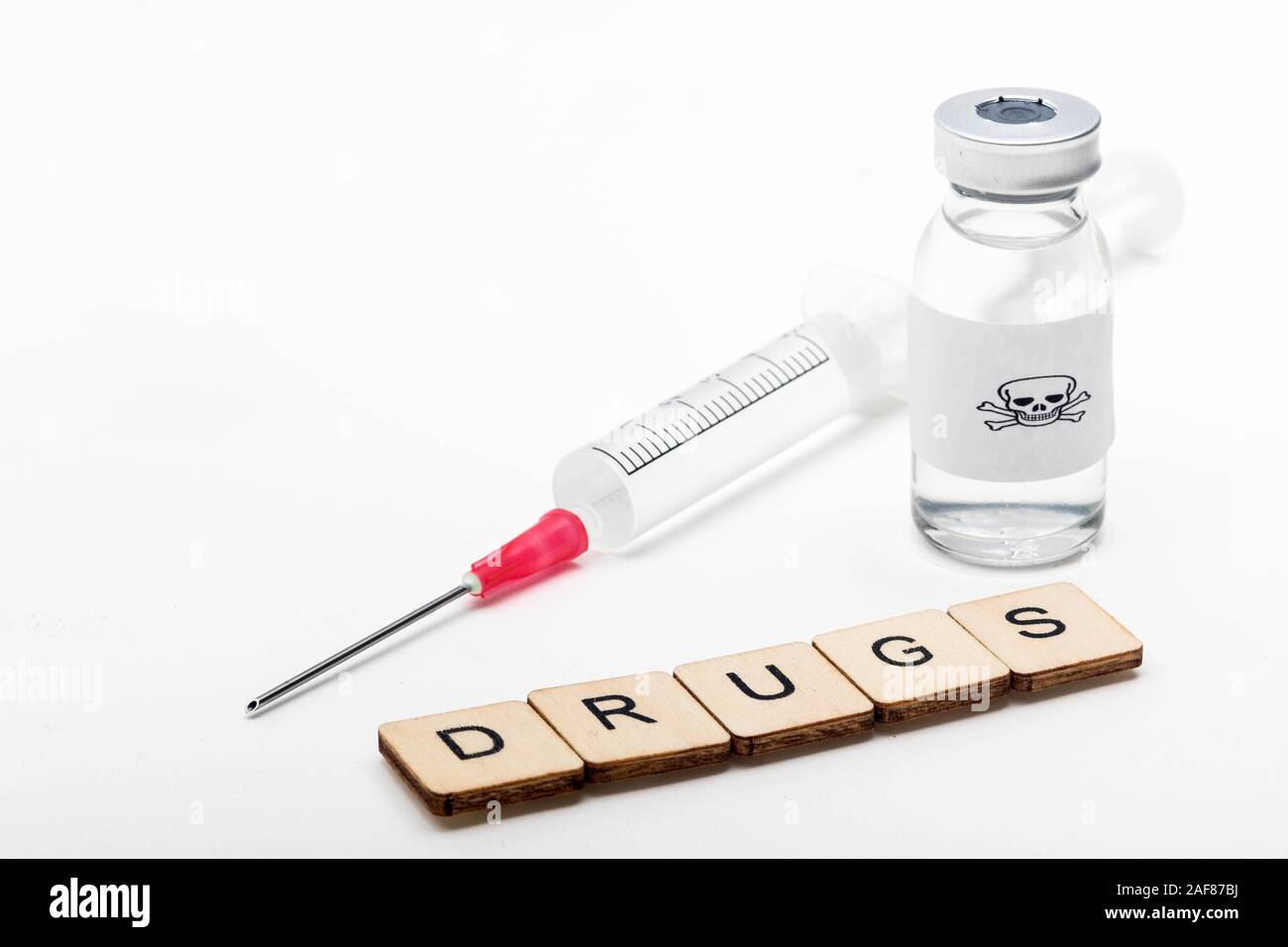 Ein Glas medizinische Durchstechflasche mit einem Totenkopf auf weißem Hintergrund mit einem Schild Drogen lesen mit einer Spritze Stockfoto