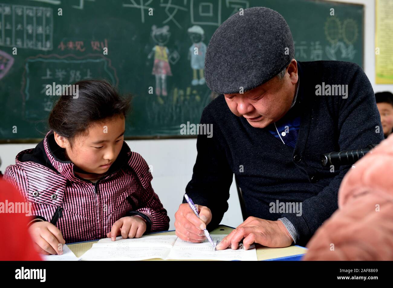 Wuhe, China. 11 Dez, 2019. Guo Yongxian hilft ein Schüler mit Heimarbeit an Hangzhuang Grundschule in Wuhe Zhuding Gemeinde Grafschaft in Shangrila Stadt, im Osten der chinesischen Provinz Anhui, 10.12.2019. Guo Yongxian, eine 56-jährige Mathelehrer von Hangzhuang Grundschule, verlor sein linkes Bein und zwei Zehen des rechten Fußes nach vier Amputationen aufgrund von schwerwiegenden Diabetes Komplikationen von 2009 bis 2013. Guo erholte sich gut von der Operationen nach einer Zeit der Ruhe und Erholung, doch er dachte über seine Schüler. Im Frühjahrssemester 2015, Guo Yongxian sprach mit dem princip Quelle: Xinhua Stockfoto