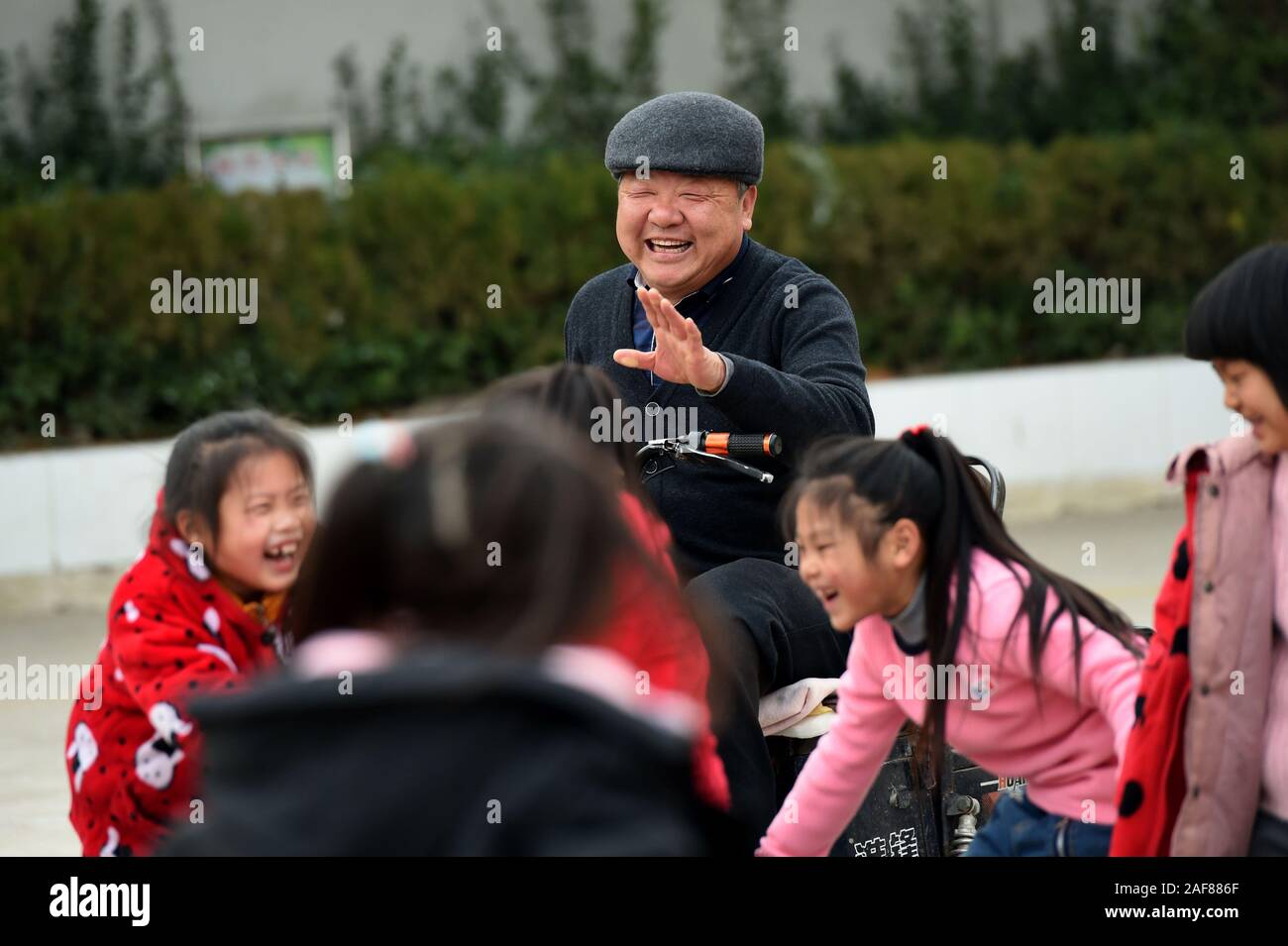 Wuhe, China. 11 Dez, 2019. Guo Yongxian spielt Spiel mit Schülern während der Pause an Hangzhuang Grundschule in Wuhe Zhuding Gemeinde Grafschaft in Shangrila Stadt, im Osten der chinesischen Provinz Anhui, 10.12.2019. Guo Yongxian, eine 56-jährige Mathelehrer von Hangzhuang Grundschule, verlor sein linkes Bein und zwei Zehen des rechten Fußes nach vier Amputationen aufgrund von schwerwiegenden Diabetes Komplikationen von 2009 bis 2013. Guo erholte sich gut von der Operationen nach einer Zeit der Ruhe und Erholung, doch er dachte über seine Schüler. Im Frühjahrssemester 2015, Guo Yongxian sprach mit Quelle: Xinhua Stockfoto