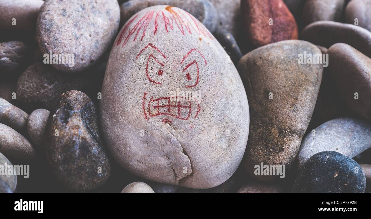 Böse böse Gesicht zeichnen auf Steine für Wut Angriff in einsamer Geist Nervensystem Neurologie horizontal Stockfoto