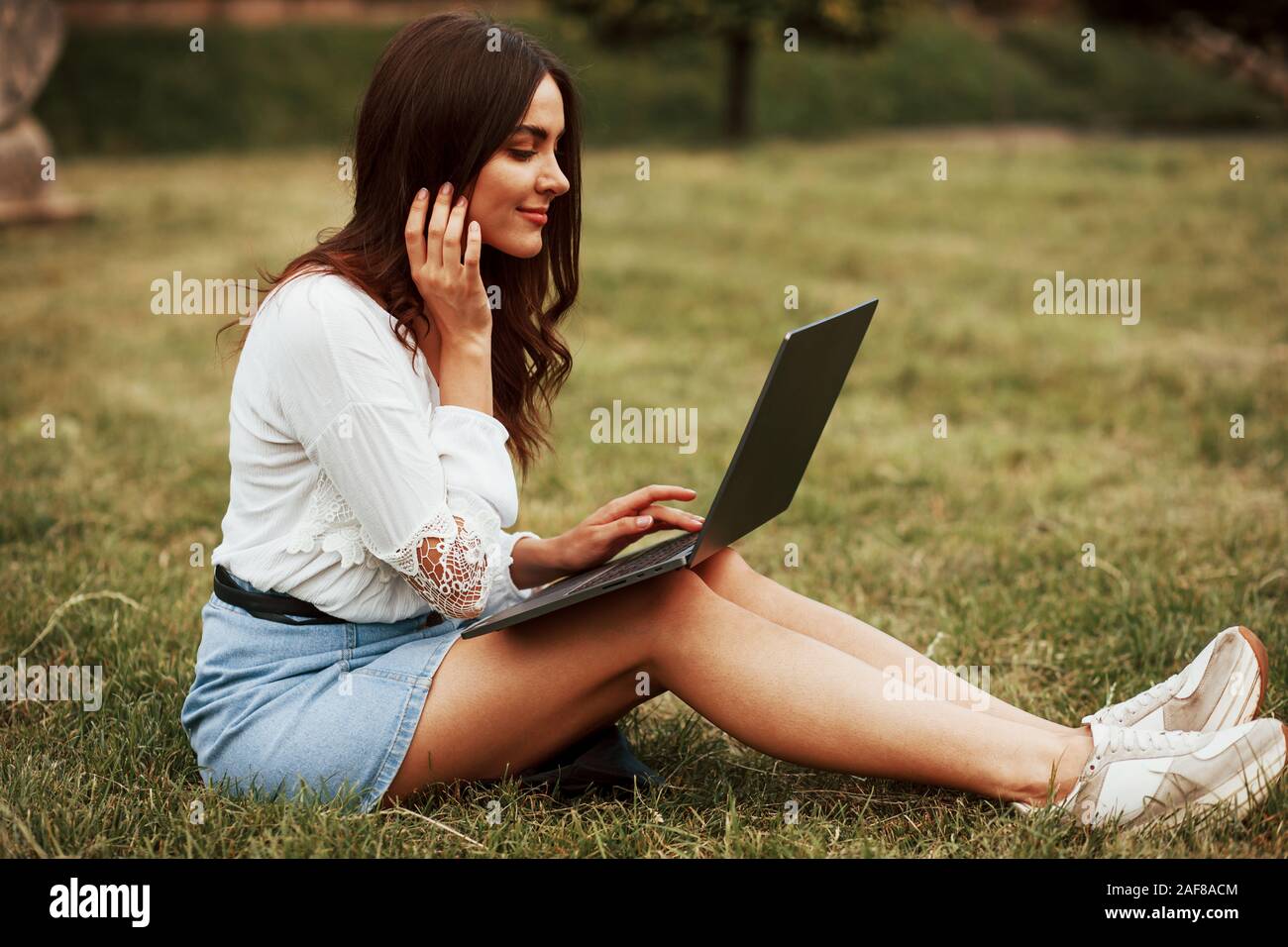 Drahtlose Technologien. Junge Frau Wochenende haben und sitzt im Park am Tag Stockfoto