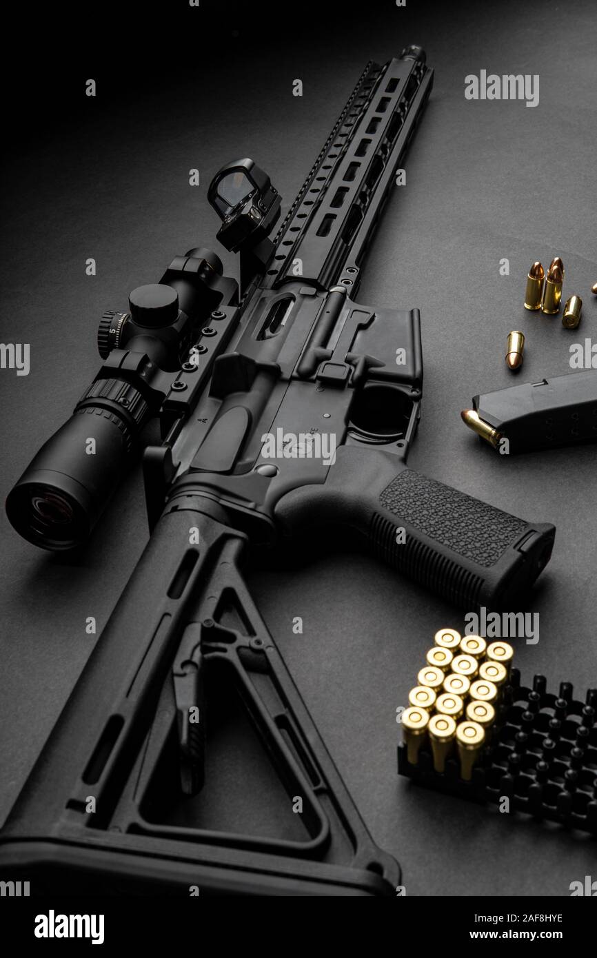 Moderne automatische Karabiner mit optischen und Kollimator Anblick. Ein Gewehr mit zwei Sehenswürdigkeiten vor einem dunklen Hintergrund. Patronen für Waffen in der Nähe von einen Karabiner. Stockfoto