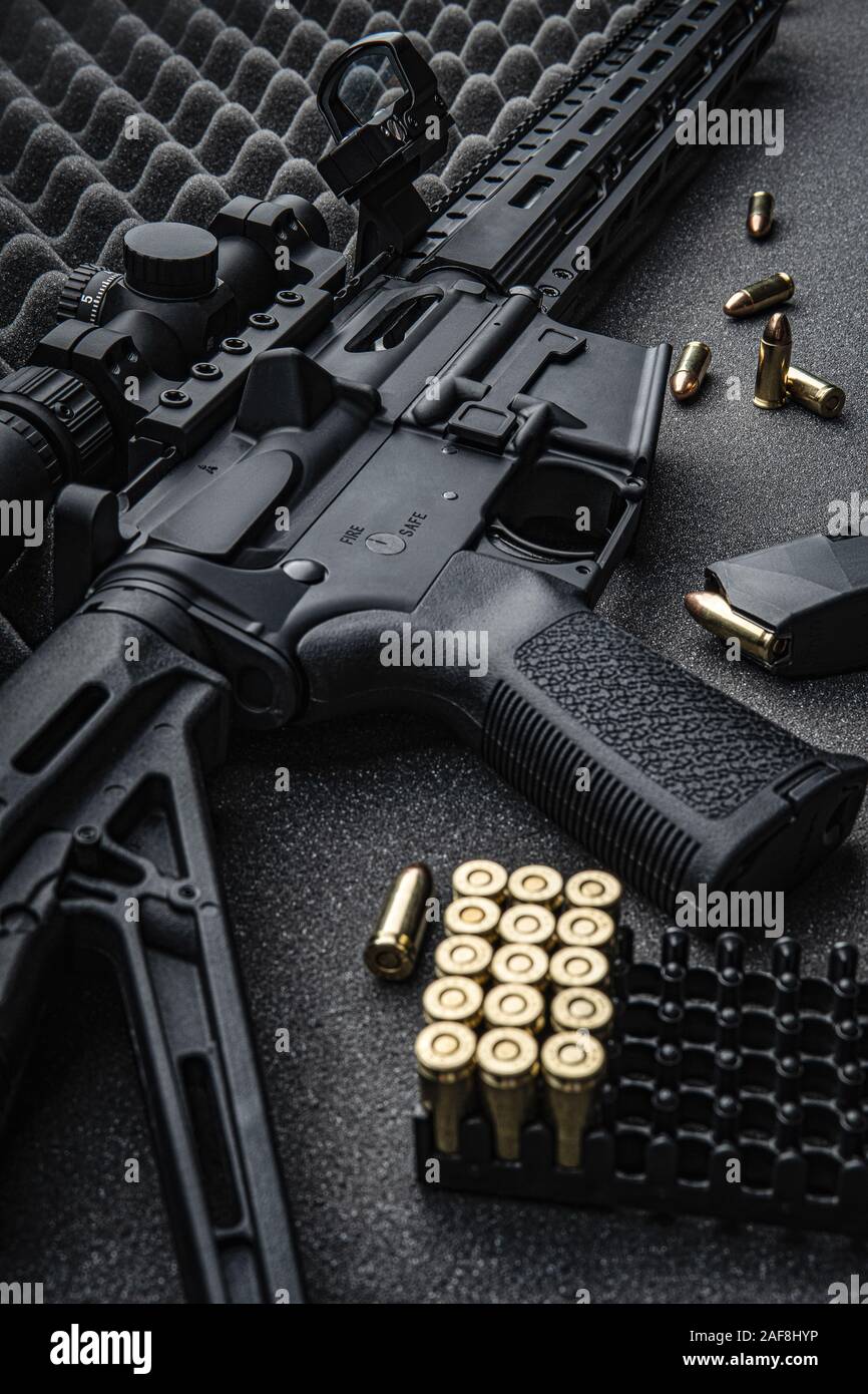 Moderne automatische Karabiner mit optischen und Kollimator Anblick. Ein Gewehr mit zwei Sehenswürdigkeiten vor einem dunklen Hintergrund. Patronen für Waffen in der Nähe von einen Karabiner. Stockfoto