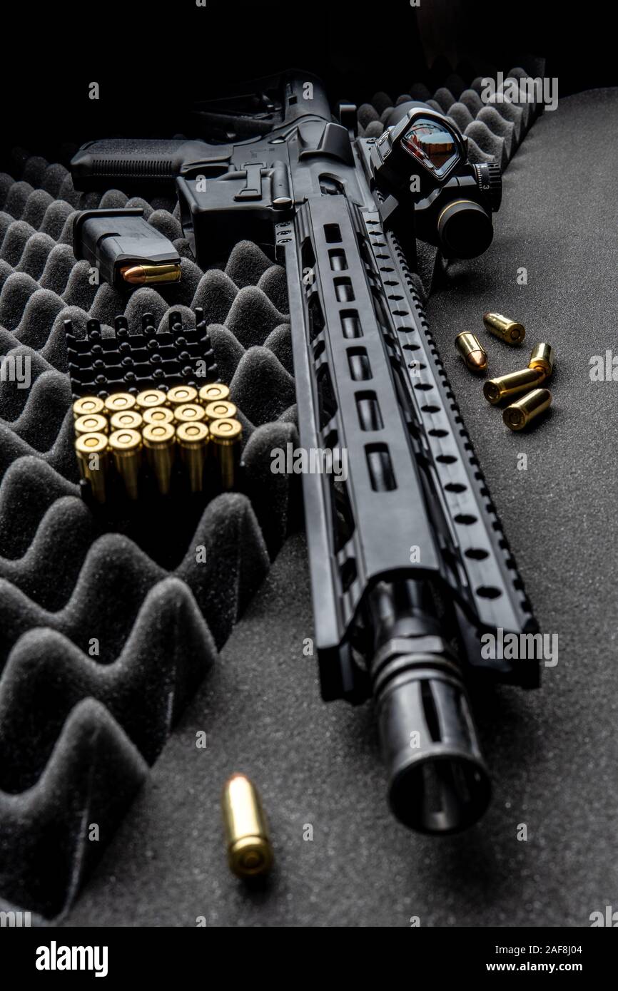 Moderne automatische Karabiner mit optischen und Kollimator Anblick. Ein Gewehr mit zwei Sehenswürdigkeiten vor einem dunklen Hintergrund. Patronen für Waffen in der Nähe von einen Karabiner. Stockfoto