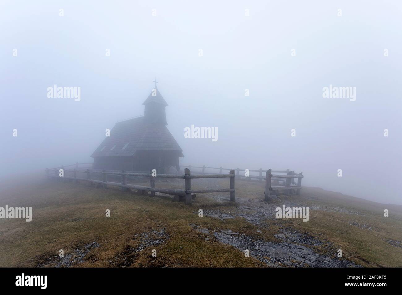 Traditionelle malerischen Kirche aus Holz auf der Hochalm Velika Planina im Nebel. Stockfoto