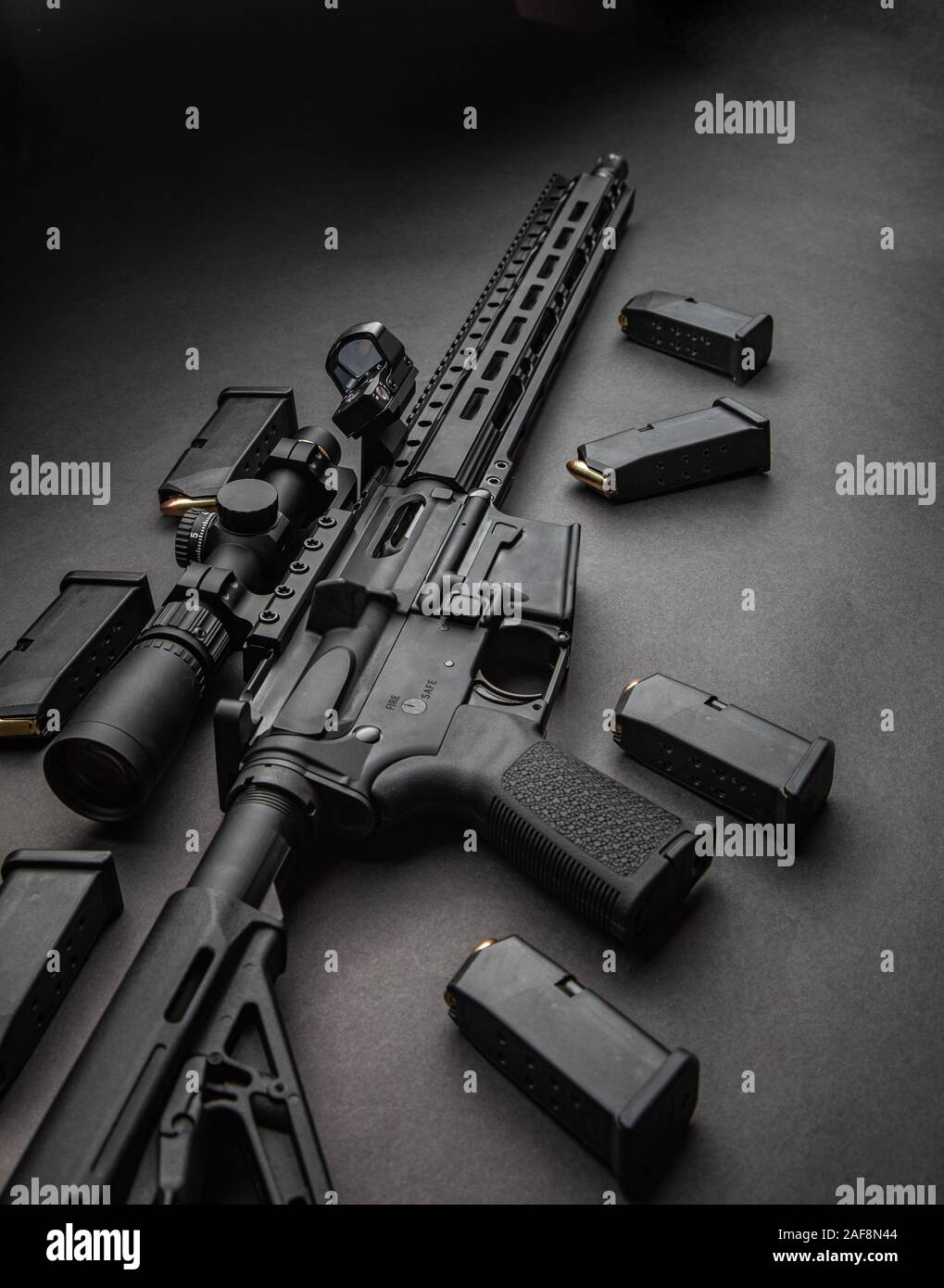 Moderne automatische Karabiner mit optischen und Kollimator Anblick. Ein Gewehr mit zwei Sehenswürdigkeiten vor einem dunklen Hintergrund. Patronen für Waffen in der Nähe von einen Karabiner. Stockfoto