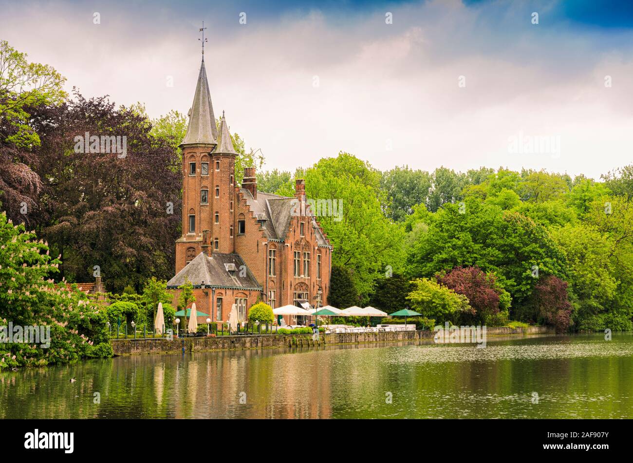 Panoramablick auf See der Liebe durch die Bäume und Pflanzen von Minnewasserpark in der alten Stadt von Bruges umgeben. Belgien Stockfoto