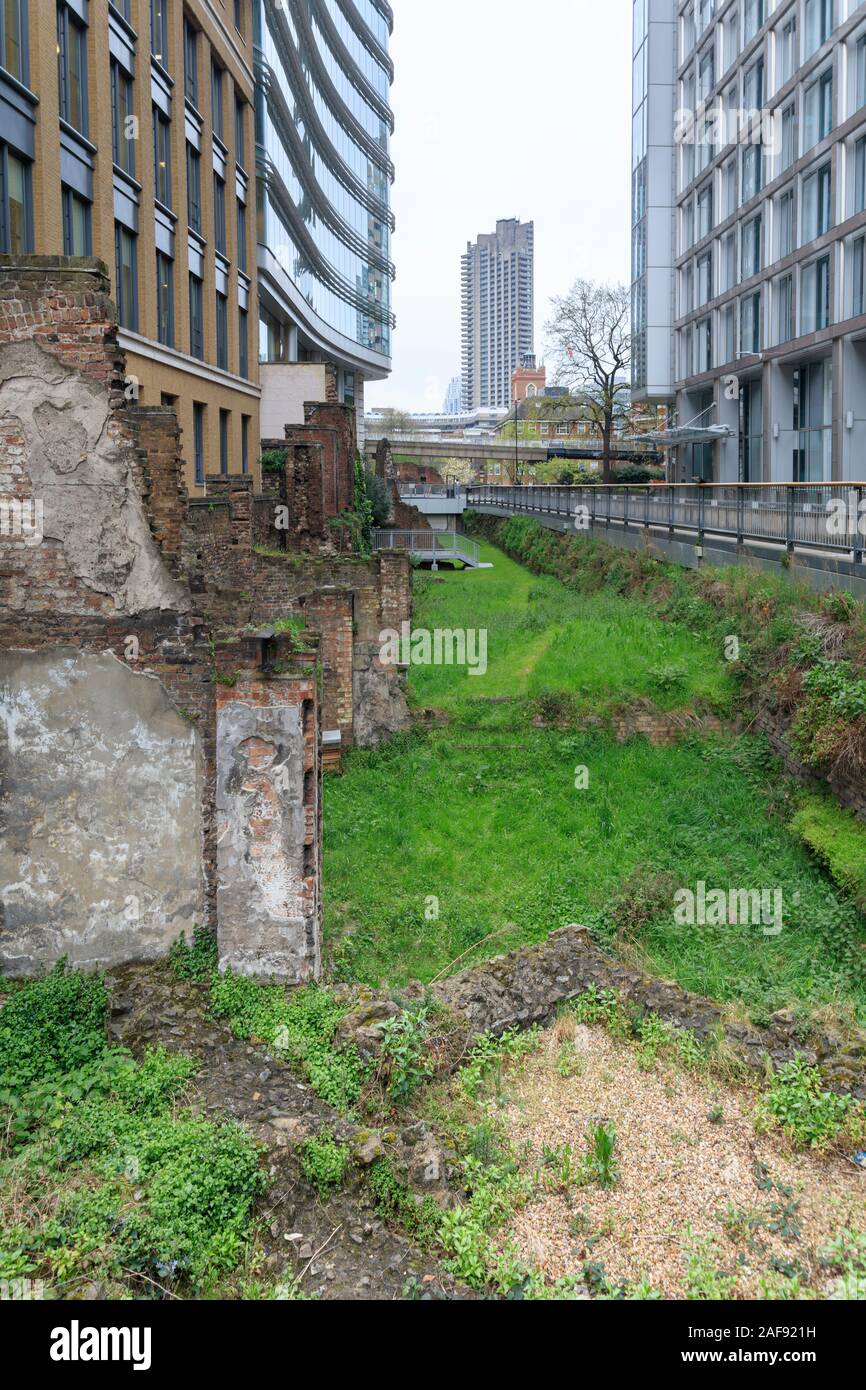 Ein Blitz Bombe site mit einer freiliegenden Stück original Londoner des Mittelalters und der Römischen Mauern und eine römische Bastion, Noble Street Gardens, London Stockfoto