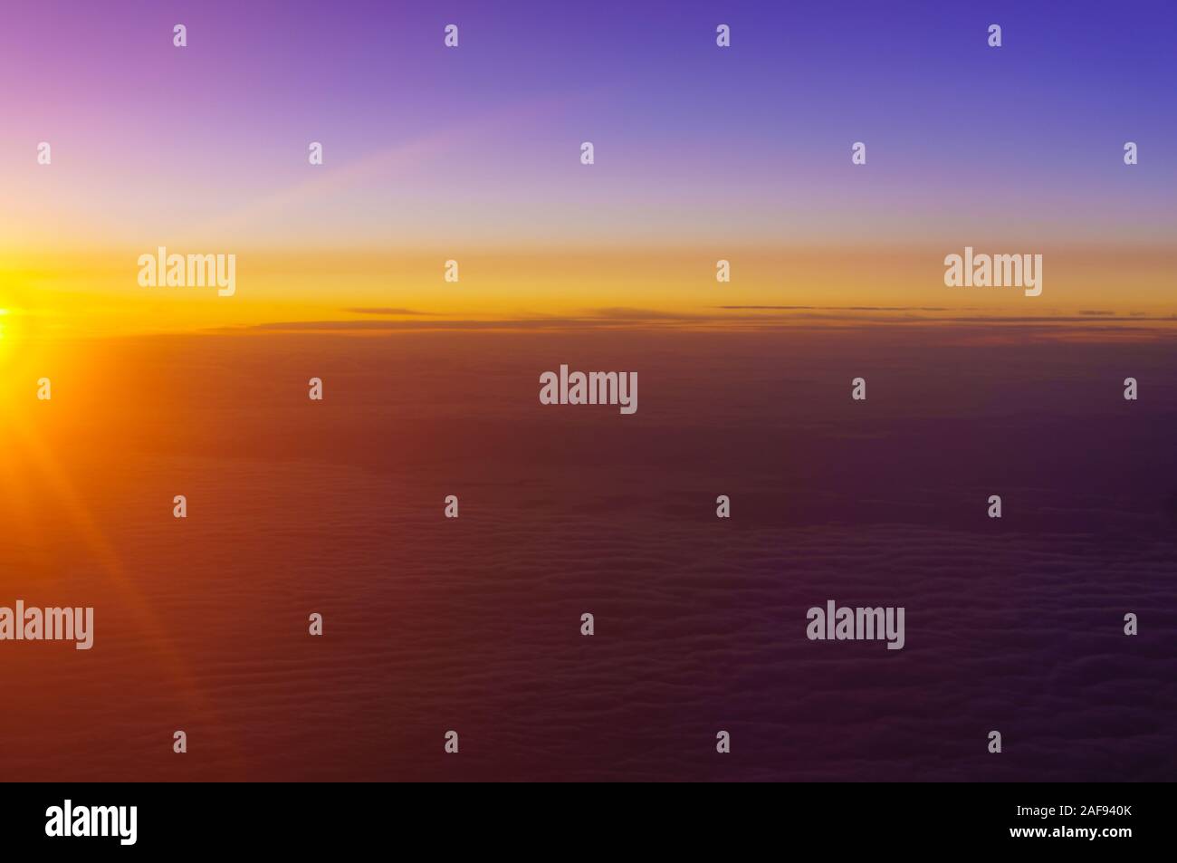 Die aufgehende Sonne beleuchtet die Wolken über der Erde. Sonnenaufgang über den Wolken. Der Blick aus dem Fenster des Flugzeugs. Stockfoto