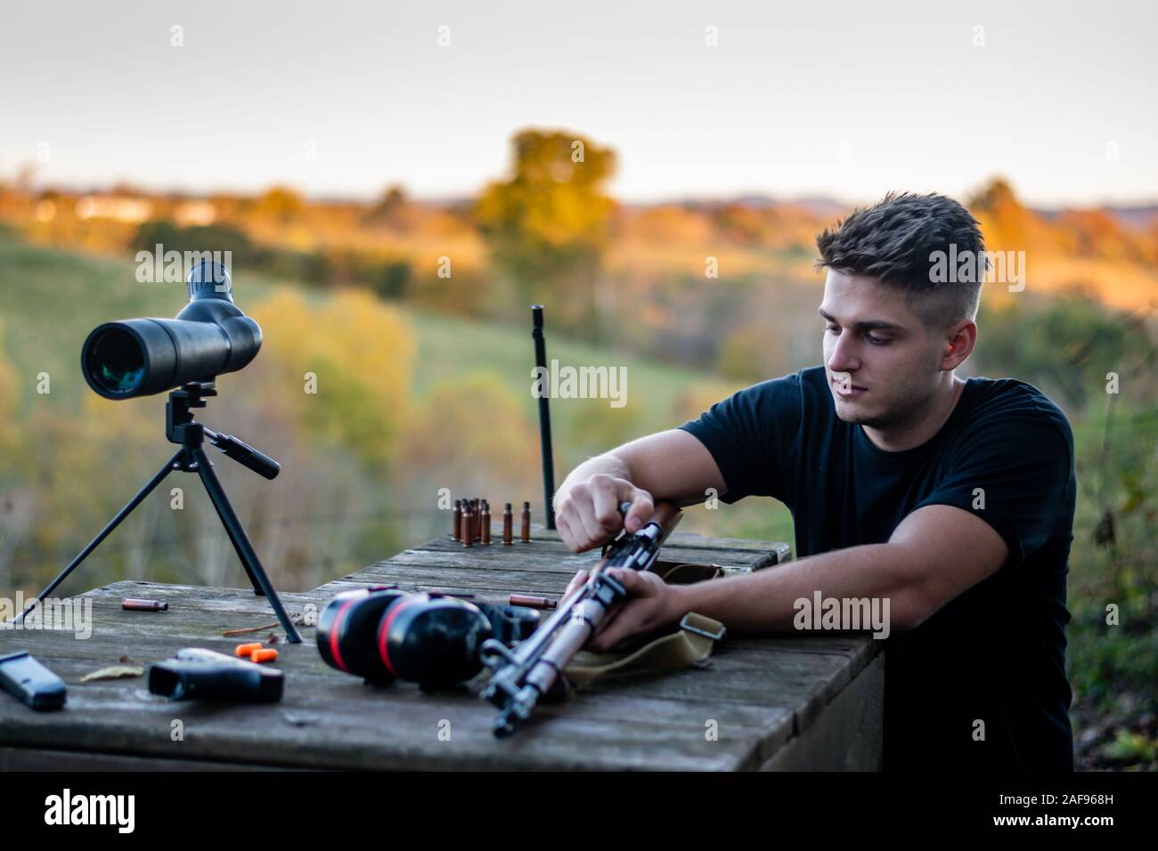 junges kaukasisches Mann, das Gewehr im Freien in den Bergen von Kentucky lädt Stockfoto