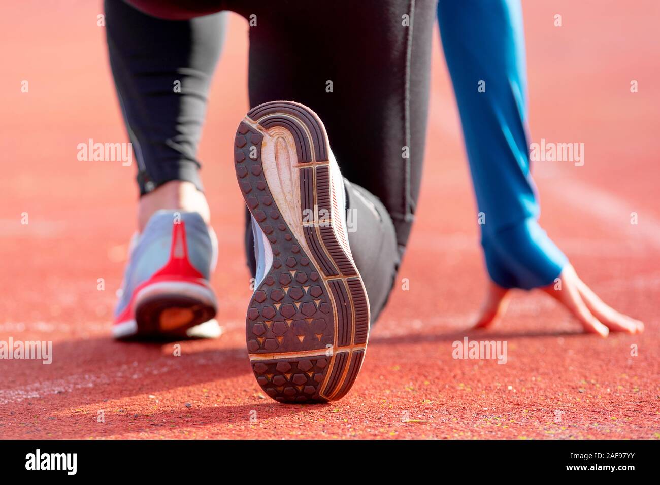 Rückansicht eines Athleten erhalten für das Rennen auf einem laufenden Track bereit. Fokus auf Schuh eines Athleten zu einem Rennen im Stadion. Stockfoto