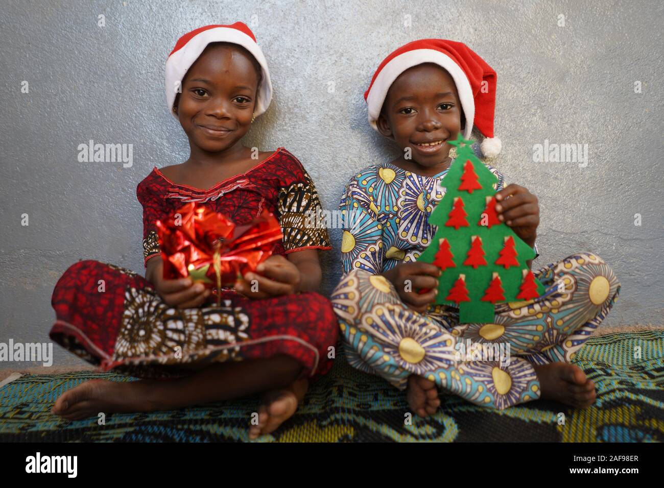 Zwei traumhaft schöne afrikanische Kinder lächeln für Weihnachtsgeschenke Stockfoto