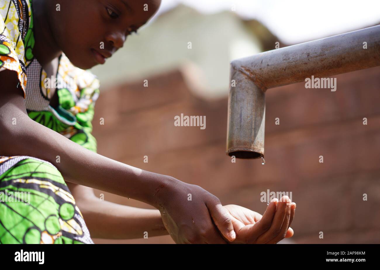 Wunderschönes afrikanisches junges Mädchen, das die Hände Im Freien mit Süßwasser waschen kann Stockfoto