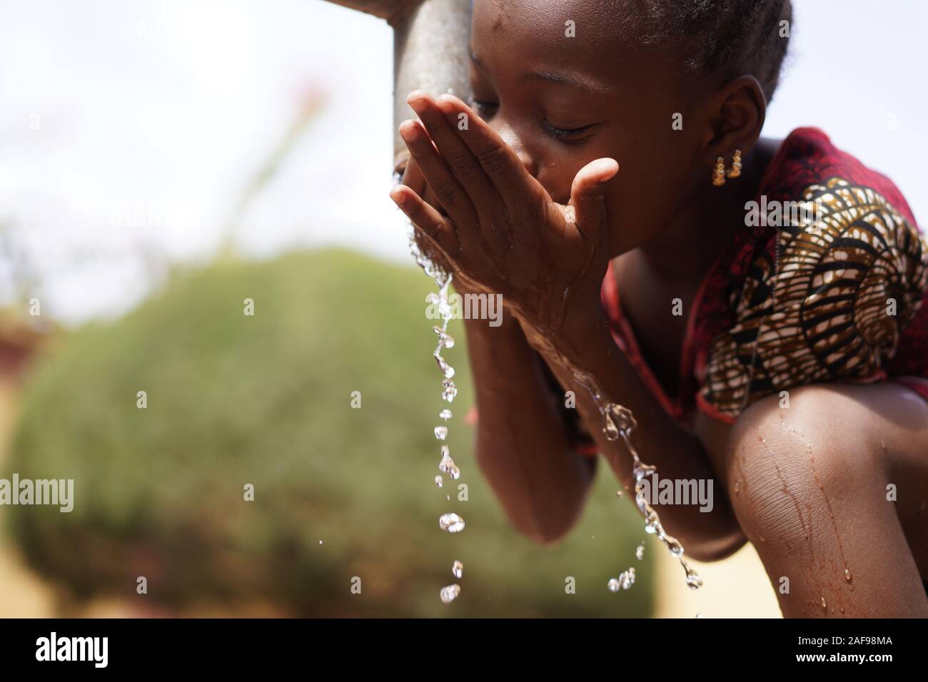 Symbol für Menschenrechte und Klimawandel: Afrikanische schwarze Ethnicity Girl Woman Trinkt sicheres Wasser Stockfoto