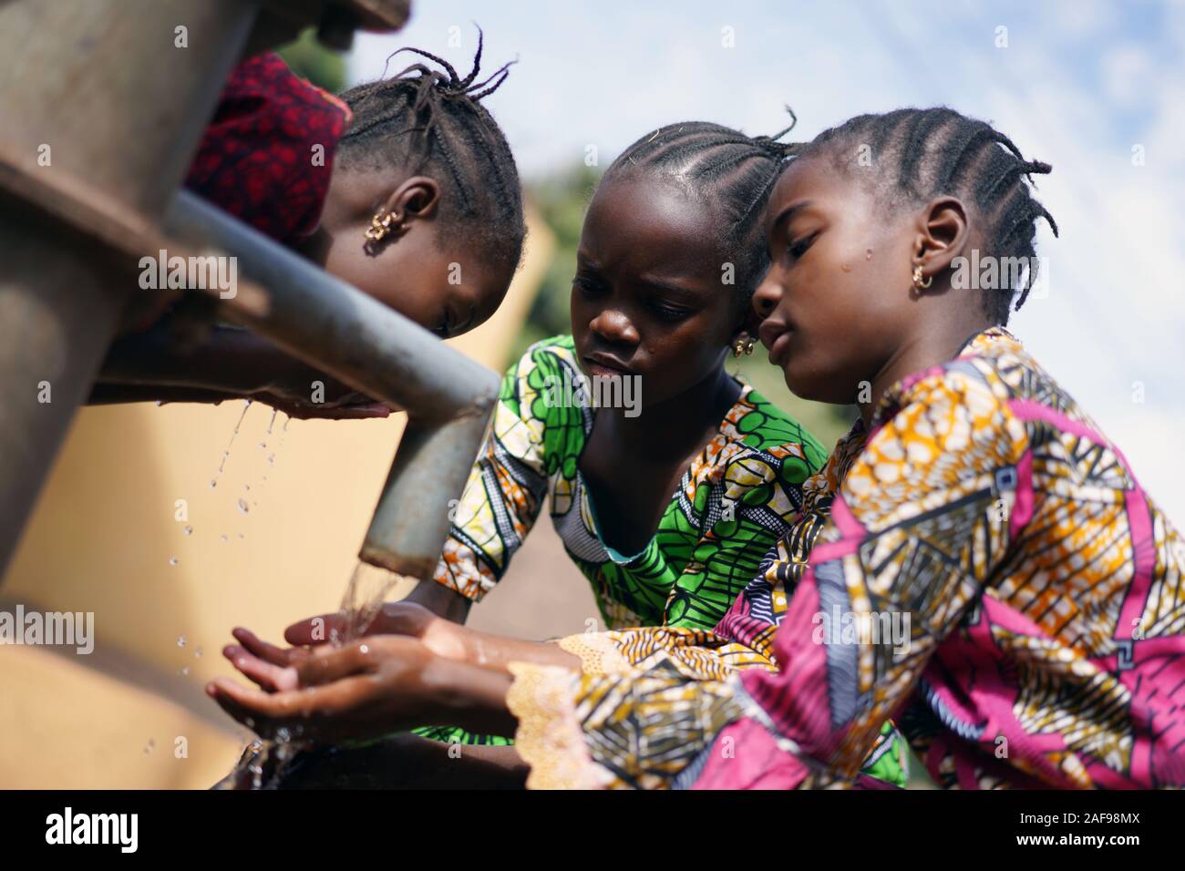 Afrikanische Frauen mit Händen unter Wasserhahn Stockfoto