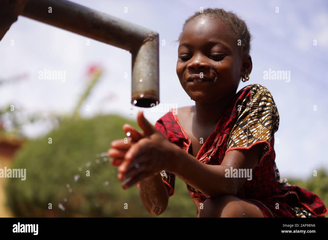 Fröhliches Kleines afrikanisches Schulmädchen Trinkt sicheres, Sauberes Wasser vom Home Tap Stockfoto