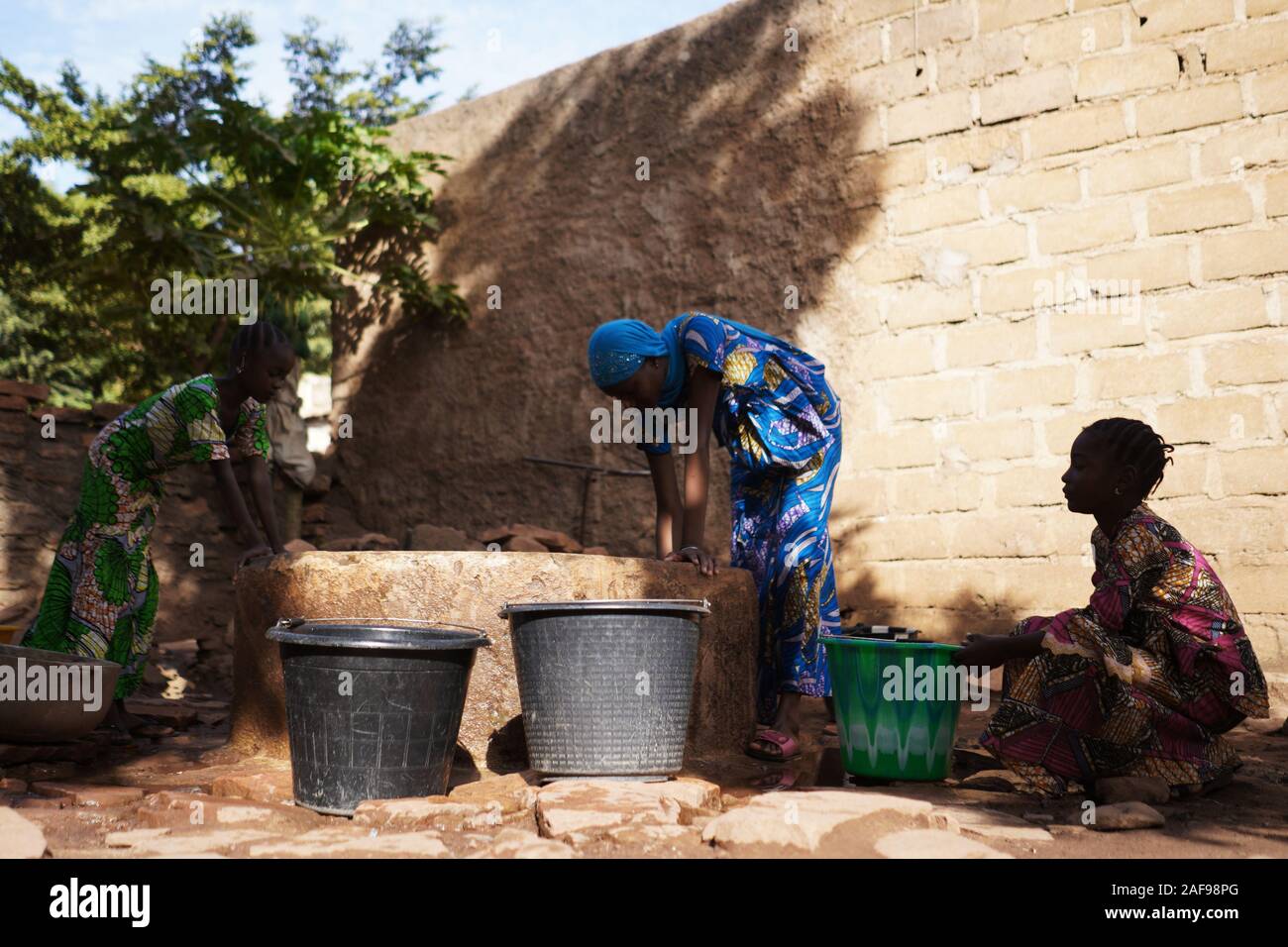 Schwarze afrikanische Frauen gießt Wasser in den Eimer Stockfoto