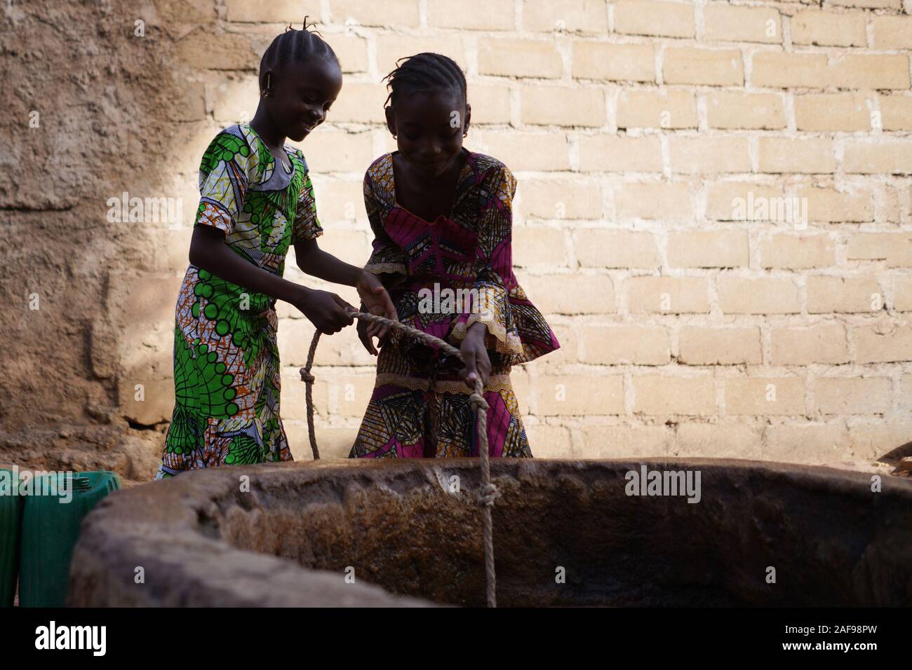 Silhouette Schuß von zwei afrikanischen Mädchen Sammeln von Wasser aus einem Brunnen Stockfoto