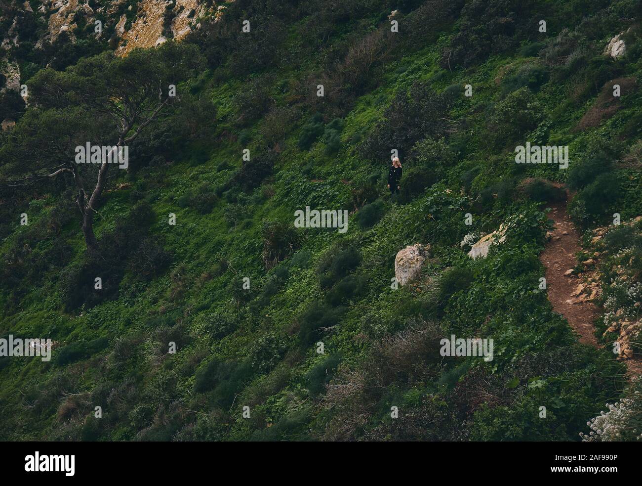 Frau beim Klettern im Naturpark Penyal d'Ifac, die auf einem Bergpfad steht, der auf der wunderschönen Natur in Calpe posiert Stockfoto