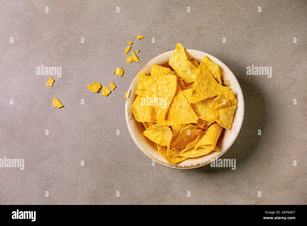 Tortilla nachos Mais Chips in Keramik Schüssel über braune Textur Hintergrund. Flach, Raum Stockfoto