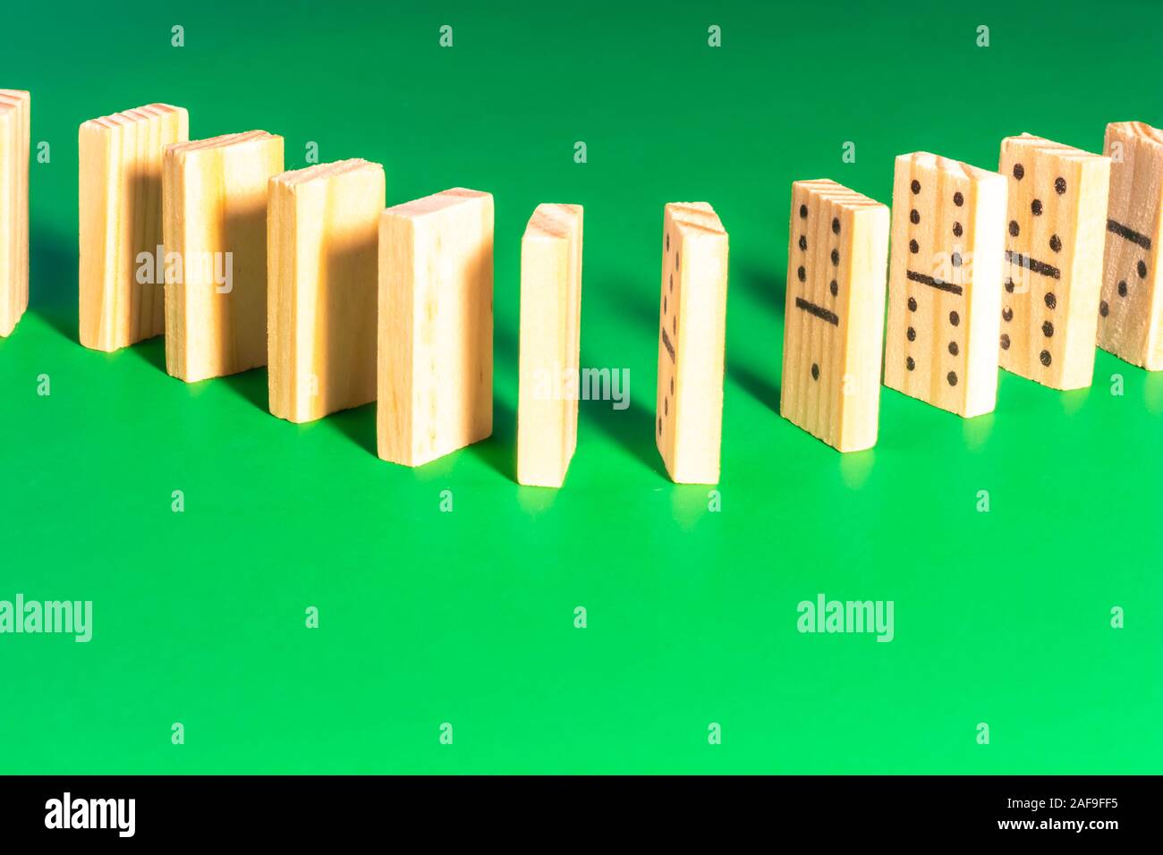 Eine Kurve in einer Linie ausgerichtet sind Holz- Domino steht auf einem soliden grüne Fläche. Die Steine sind nicht für das Spiel konfiguriert, aber für Klopfen o Stockfoto
