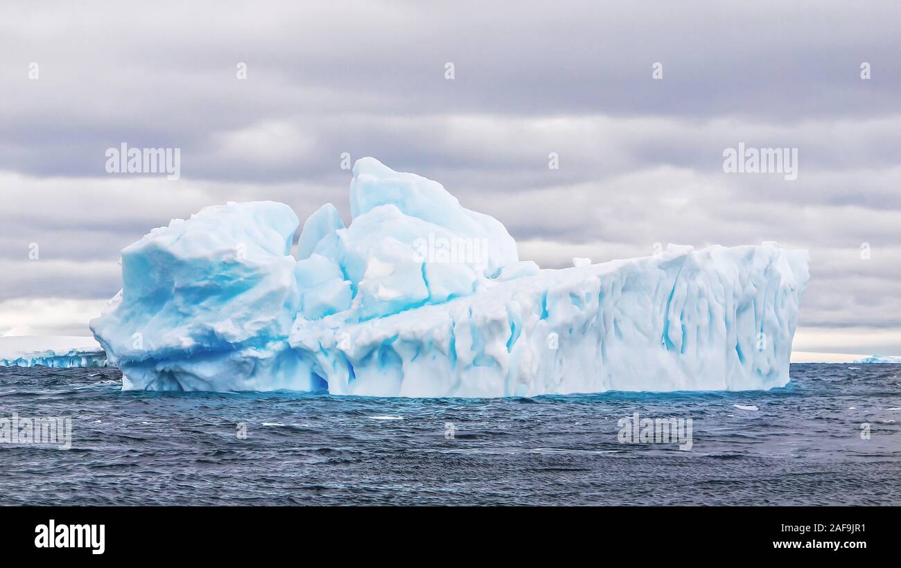 Ein großer Eisberg floating im Weddellmeer in der Antarktis, zeigt seine natürliche Form, blau Eis, und tiefe Risse in seiner Struktur. Stockfoto