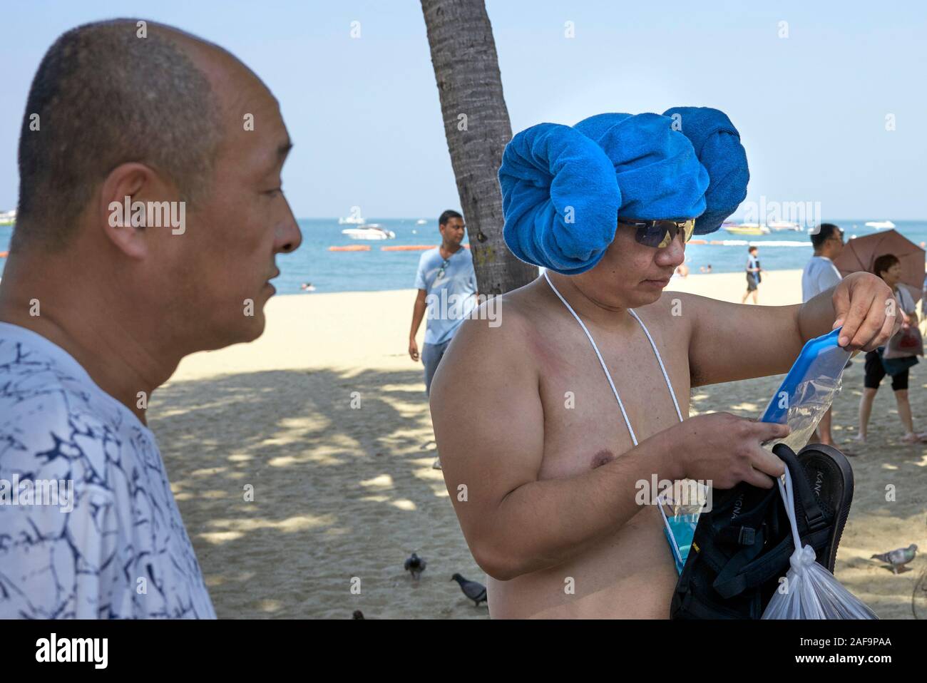 Chinesischer Mann phantasievoll Anpassung ein Handtuch als Sonnenschirm Stockfoto